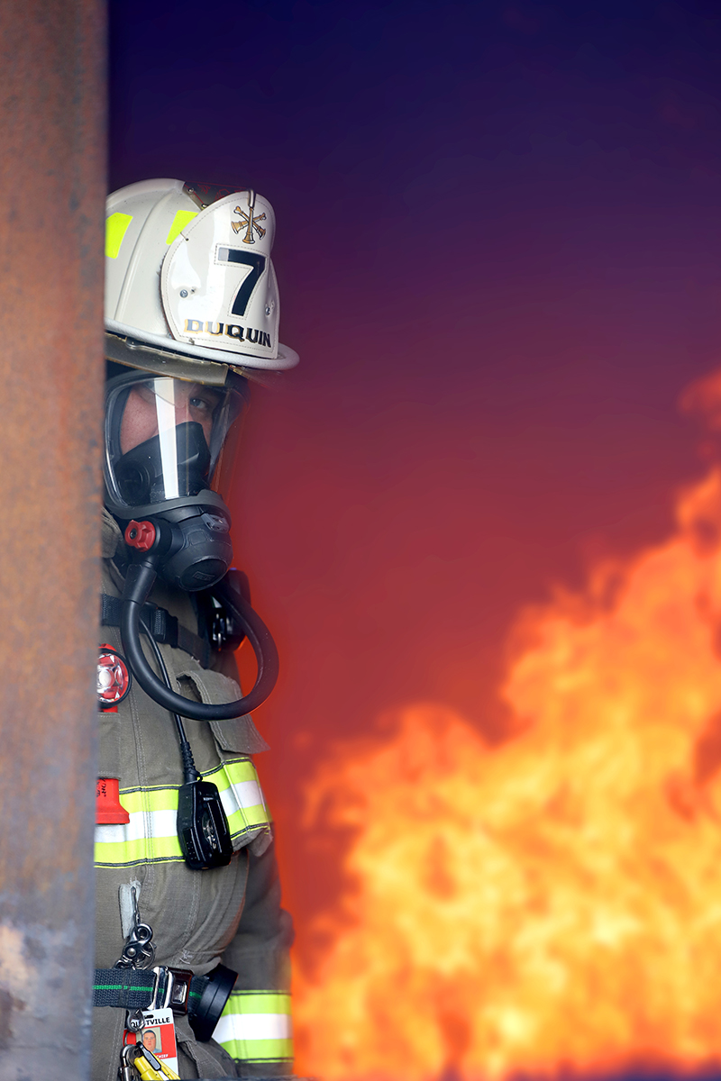 A firefighter standing in doorway of a building on fire